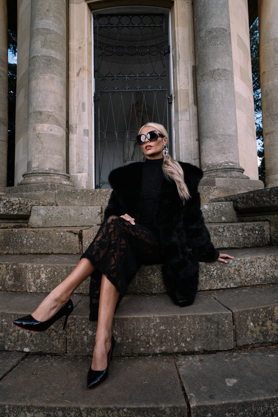 a-woman-in-a-black-outfit-sits-on-stone-steps-towdhkwe4mm